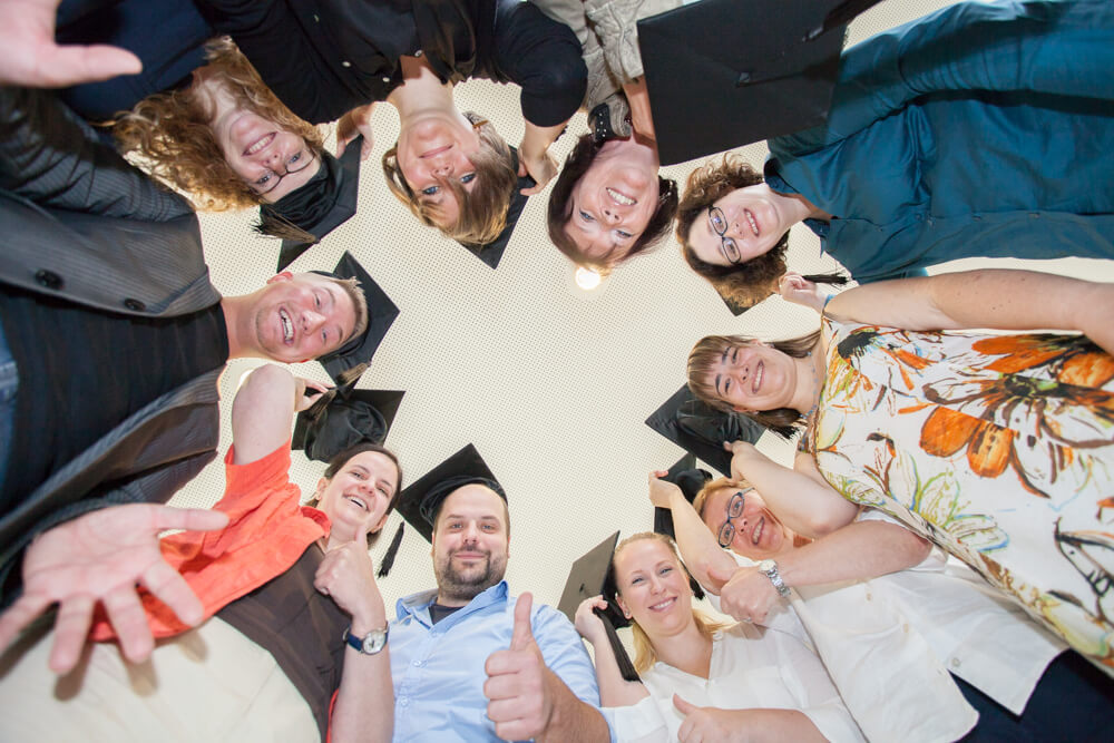 Die Teilnehmer des Onlinekurses zum Social Media Manager stehen im Kreis und blicken von oben auf die Kamera herunter